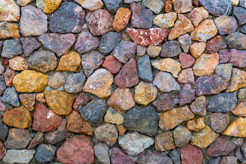 colored unprocessed rocky stones of natural origin, a wall of stones in concrete, background for walls and wallpapers