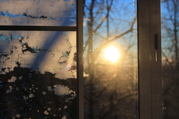 Winter sun through the window. Frozen window glass under the sun.