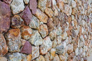 colored unprocessed rocky stones of natural origin, a wall of stones in concrete, background for walls and wallpapers