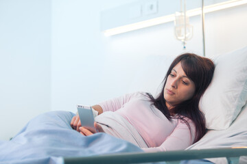 Female patient at the hospital and chatting with smartphone.