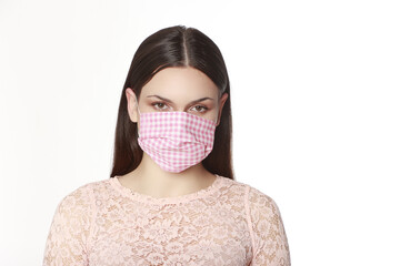 Jeune femme isolée sur fond blanc portant un masque grand public imprimé Vichy pour se protéger...