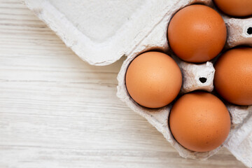 Raw Brown Eggs in a paper box, top view. Flat lay, overhead, from above. Space for text.