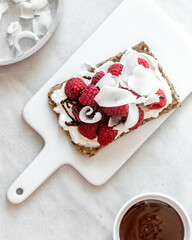 Snack with crispbread,cream cheese and fresh raspberries on white marble background. Healthy food concept.