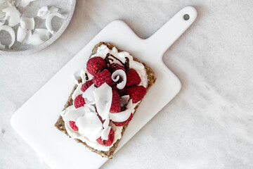 Fototapeta na wymiar Snack with crispbread,cream cheese and fresh raspberries on white marble background. Healthy food concept.