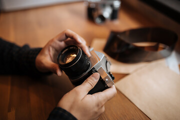 man hands adjusts the lens retro camera on a wooden table