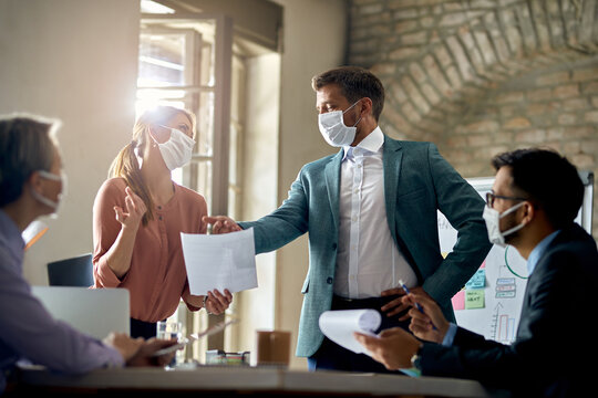 Business Coworkers Wearing Protective Face Masks While Having A Meeting During COVID-19 Epidemic.