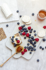 Snack with crispbread, goat cheese and fresh fruits on white marble background. Healthy food concept