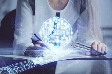 Cryptocurrency hologram over woman's hands writing background. Concept of blockchain. Double...