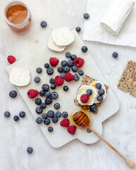Snack with crispbread, goat cheese and fresh fruits on white marble background. Healthy food concept