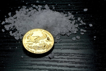 Concept: salt and gold. Gold coin American Eagle 1 ounce compared to salt as a value of life.