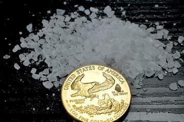Concept: salt and gold. Gold coin American Eagle 1 ounce compared to salt as a value of life.