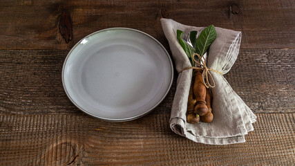 Rustic set of cutlery knife, spoon, fork with linen napkin on the plate. Old wooden table.