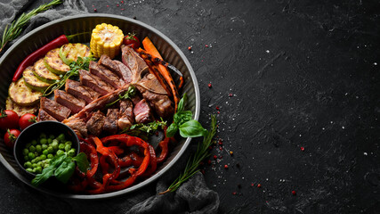 Sliced steak on the bone with grilled vegetables and spices. T-bone steak. Top view. Rustic style.