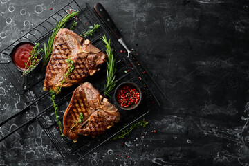 Juicy T-Bone steaks on the grill. On a black stone background. Top view. Rustic style.