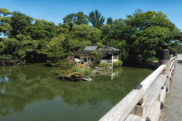 Fototapeta na wymiar 京都御苑内の旧九條家庭園、九条池の中の島にある厳島神社と池に架かる高倉橋が見える初夏の風景