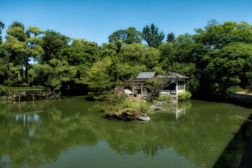Obraz premium 京都御苑内の旧九條家庭園、九条池の中の島にある厳島神社と初夏の風景
