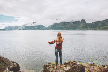 Woman looking at map planning vacation trip traveling solo in Norway active adventure lifestyle sea fjord and foggy mountains landscape