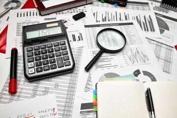 Top view of office employee's desk - work with financial reports, analysis and accounting, tables and graphs, various office items for bookkeeping