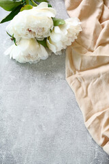 Peony flowers and beige cloth on grey stone background. Vertical greeting card mockup for birthday, Mother's Day, Woman's day, wedding