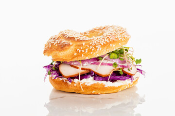 fresh delicious bagel with meat, red onion, cream cheese and sprouts on white background