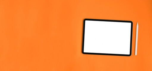 Computer tablet and stylus pen are putting together on orange background.