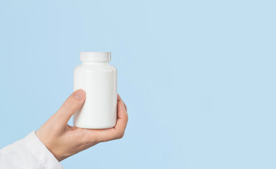 Hand of female doctor holds white pills or tablets jar mockup. Medicine and pharmacy, prescription drugs or vitamins concept. Copy space banner