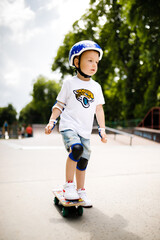 Boy with a skate in a skate park. The boy learns to skate, in full protection.