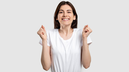 Winning gesture. Victory success. Happy excited woman raising clenched fists isolated on light...