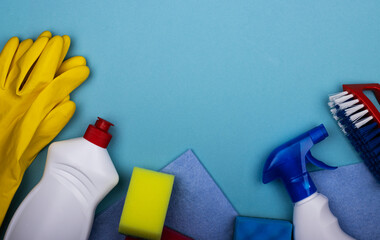 cleaning products in plastic bottles, rubber gloves with a sponge on a blue background, top view