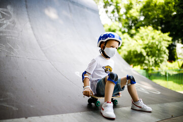 A boy with a skate in a mask, learning to skate, in full protection in quarantine.