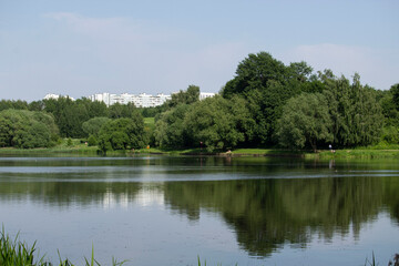 Fototapeta na wymiar Multistorey building in the park on the bank of the river