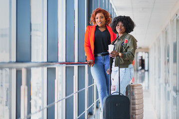 Two african girls with suitcases at the airport. The concept of travel and vacation.