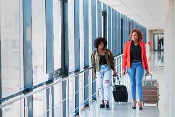 Two african girls with suitcases at the airport. The concept of travel and vacation.