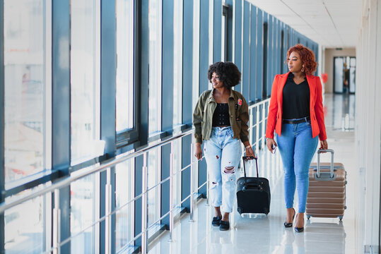 Two african girls with suitcases at the airport. The concept of travel and vacation.