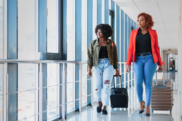 Two african girls with suitcases at the airport. The concept of travel and vacation.