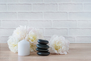 Fototapeta na wymiar Beautiuful spa and relax composition. Black massage stones, white candle and pink peonies