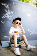 Boy with a skate in a skate park. The boy is sitting on a skateboard.