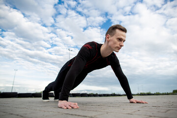 Close up of a strong young man push-up on the asphalt of the sports ground. Man training in the morning. Healthy lifestyle, sport concept. Copy space