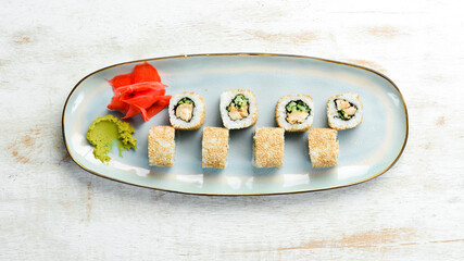 Rolls with cucumber, fish and cheese on a plate. Sushi. Top view. Rustic style.