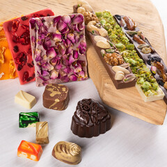 Luxury chocolate pieces, rose, pomegranate, nuts close up
