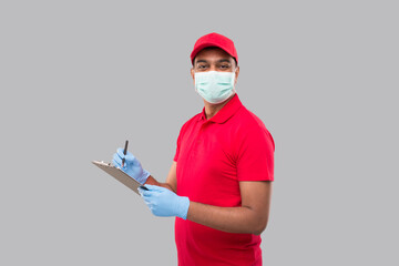 Delivery Man Writing in clipboard Wearing Medical Mask and Gloves Watching in Camera. Indian Delivery Boy Clipboard