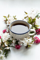 Obraz na płótnie Canvas cup of healthy black tea in front of a white background surrounded by colorful flowers