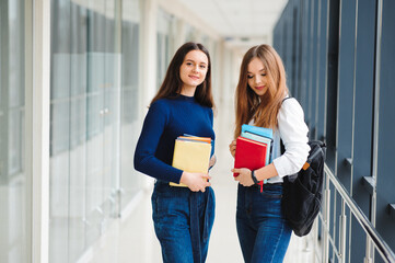 two female students stand in the corridor of the college with books