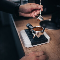 A professional barista fills the holder for an espresso machine - quick brewing of pressurized coffee