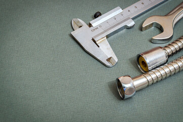 Plumbing tool and hose on dark green background are used for replacement in the shower