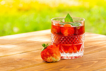 Strawberries on the table and a fresh drink with mint on sunny day