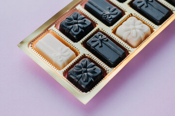 Various chocolates, Chocolate candies with filling and nuts, sweets background. Oval sweets made of black, milk and white chocolate with hazelnuts, almonds and cashews