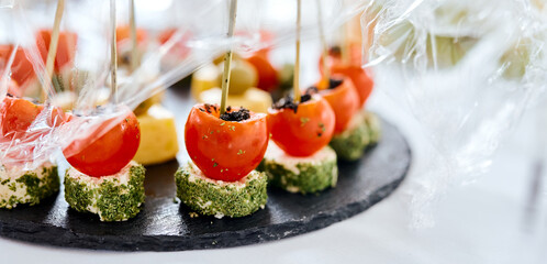 stuffed little tomatoes on a black tray Canapes Catering
