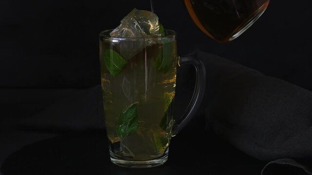 Fresh cool drink. Lemon uppercut with mint. Ice cold drink. The drink is poured into a glass with ice.