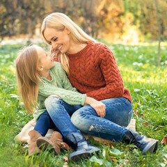 Fototapeta premium Happy smiling young caucasian mother and little daughter hugging each other outdoors. Happy family outdoor.